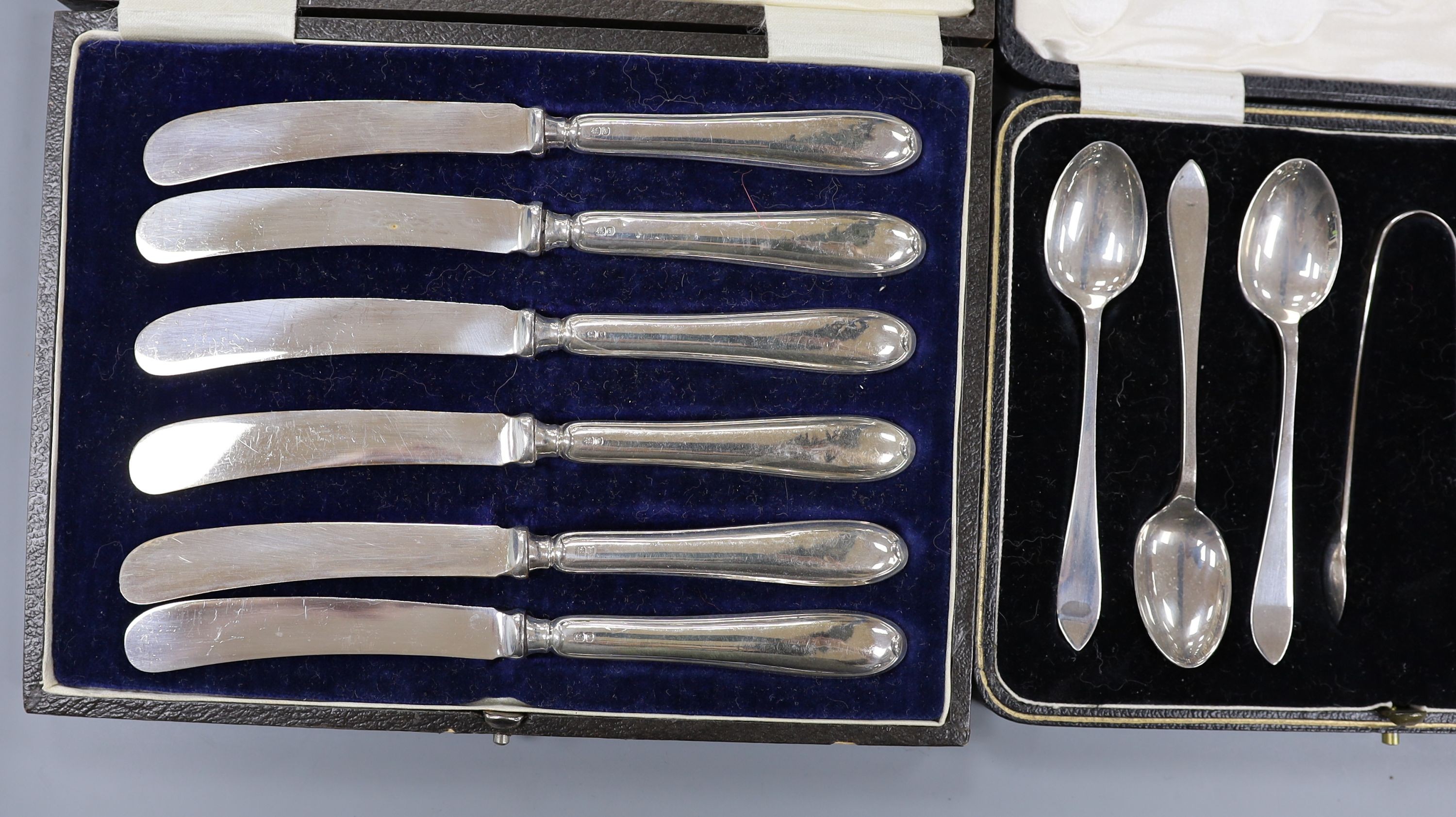 A cased set of six Danish gilt sterling and polychrome enamel coffee spoons, a cased set of six silver teaspoons with tongs and a cased set of six silver handled tea knives.